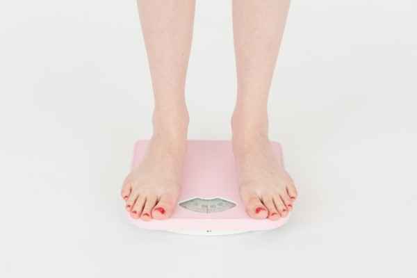 women-check-weight-on-weighting-machine