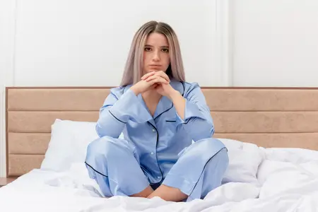 young-woman-suffering-from-anemia-sitting-on-bed-with-serious-face