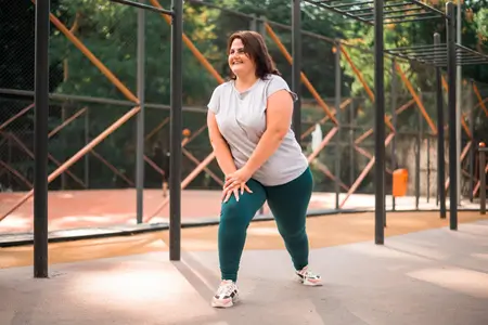 smiling-woman-with-overweight-doing-exercises-in-park