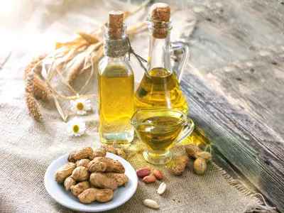 peanut cooking oil in a glass bottle with peanuts
