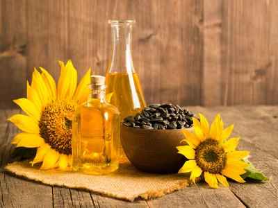 sunflower oil with flower and by seed on brown background