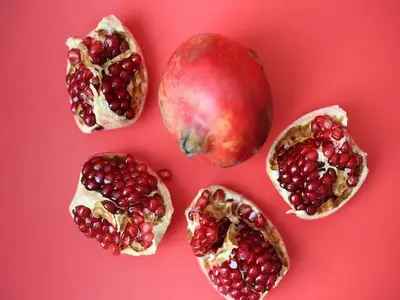 Pomegranate and pieces full of antioxident kept on red surface