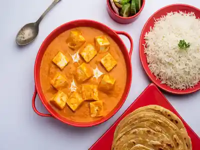 Paneer butter masala served with rice and laccha paratha