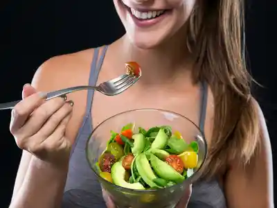 Beautiful young woman eating salad