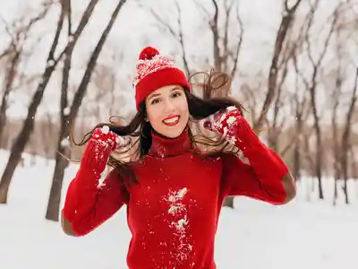 Young beautiful woman with long hair in warm clothes is enjoying the snow in the park