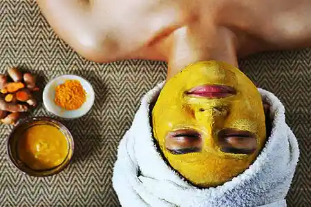 A young woman applying a turmeric face mask at home