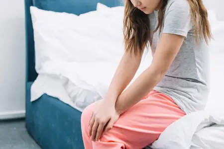 A girl sitting on the bed upset about her period