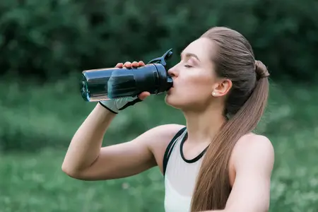 Beautiful girl drinking water after workout