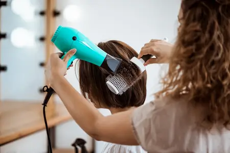 female hairstylist making hairstyle in beauty salon