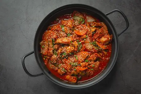 fried spicy chicken in cauldron with sauce