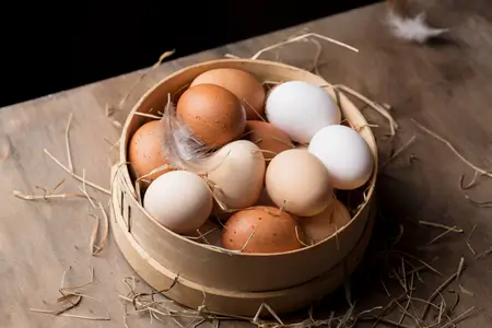chicken eggs white and red type eggs inside a wooden basket