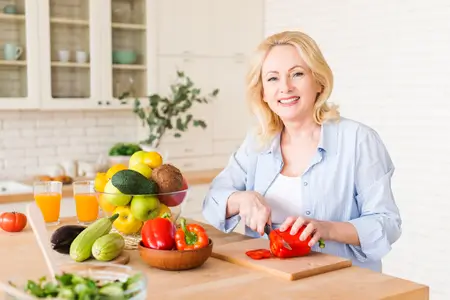 senior-woman-cutting-veggies-with-knife-in-kitchen
