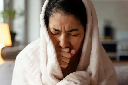 a-woman-sitting-covered-with-a-blanket-is-suffering-from-cold
