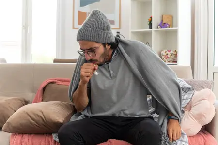 sick-young-man-wearing-a-hat-coughing